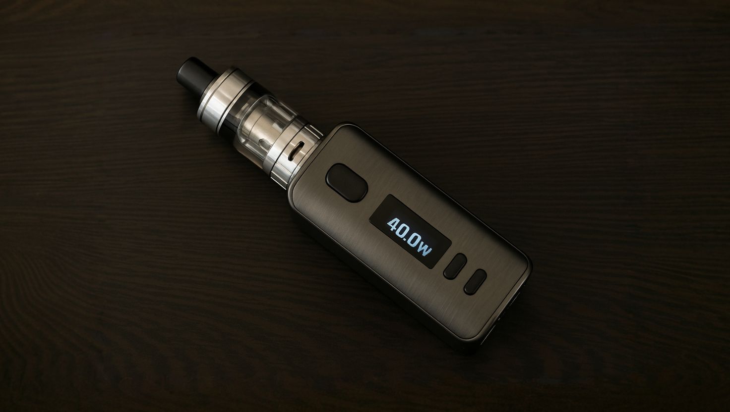 Vape-Gerät mit aktiviertem Wattage-Display auf dunklem Holz – ideal zur Erklärung der Leistungsanpassung für Anfänger